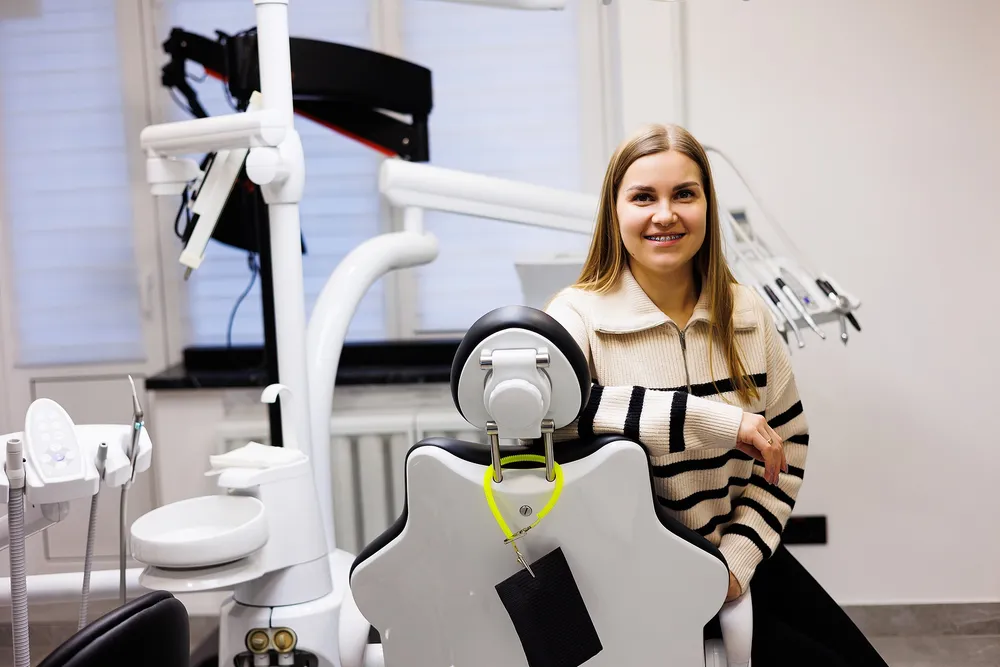A patient seated beside a dental chair in a modern clinic